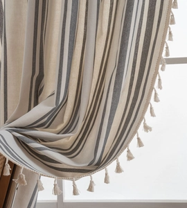 Detailed view of striped linen curtain fabric with elegant cream fringe edges and soft pleats