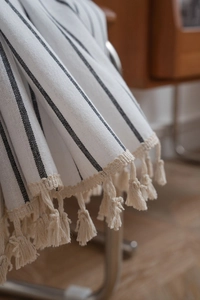 Close-up of black and white striped semi-sheer kitchen curtain with woven tassels