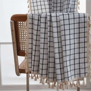 Detailed view of black and white plaid curtain fabric with decorative cream tassels
