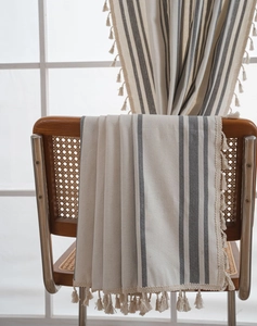 Detail of striped cotton linen curtain fabric with tassels on a rattan chair
