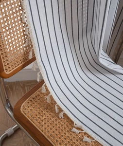 Detailed view of black and white striped linen fabric with elegant cream tassel fringe