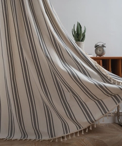 Detail of Nordic striped cotton throw blanket with handmade tassels on wooden cabinet