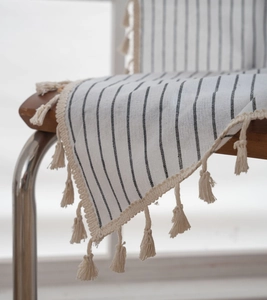 Detail of minimalist black striped cotton linen tablecloth with beige tassel fringe edge
