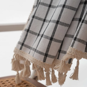Detail of black and white checkered fabric with elegant cream tassel fringe edges