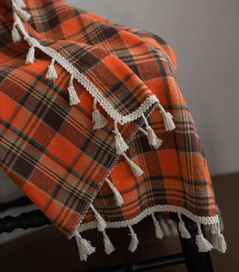 Close-up of orange and brown plaid curtain fabric with decorative cream tassels