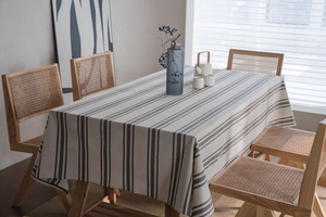 Detailed view of modern striped rectangular tablecloth on a wooden table with dining chairs