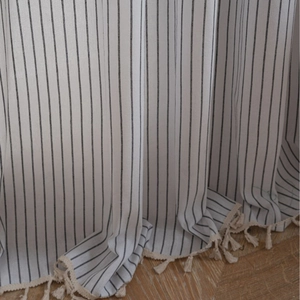 French striped linen curtain with elegant bottom tassels on wooden herringbone floor