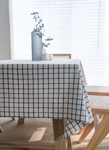 Close-up of black and white checkered linen tablecloth on a rustic wooden dining table