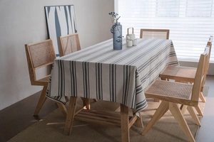 Detail of grey and blue striped linen tablecloth draped over a wooden dining table