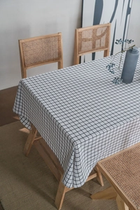 Detailed view of black and white checkered linen tablecloth with natural drape on a table