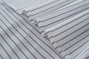 Close-up of fine black stripes on white cotton linen fabric with detailed sewing