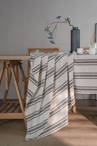 Detail of grey striped linen tablecloth draping over a wooden table in a Nordic setting