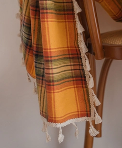 Detail of orange plaid curtains fabric with tassels draped on a wooden chair