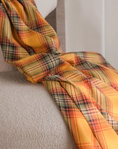 Close-up of orange plaid fabric texture with twill weave on a soft bouclé chair