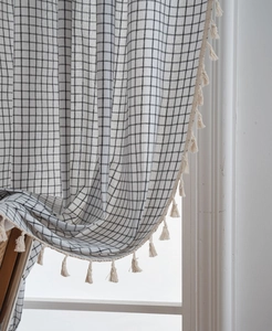 Close-up of black and white checkered curtain with elegant cream fringe tassels
