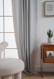Detail view of black and white checkered curtain with elegant beige tassel edge trim
