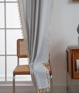 Detail of black and white checkered curtain with elegant tassel fringe on cotton linen fabric