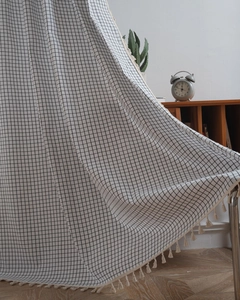 Detailed macro view of black and white grid curtain fabric with cotton tassel fringe