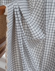 Close-up of black and white checkered cotton linen curtain with cream fringe tassels