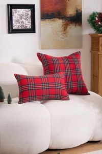 Detail of red and green plaid Christmas pillow covers on a white sofa in a festive setting