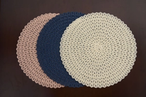 Close-up of bohemian round woven placemats with hollow out lace in pink, navy and beige