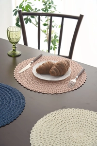 Detail of round woven placemats with scalloped edges in pink, blue, and cream colors