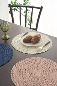 Close-up of modern round woven placemats with hollow tassel edges in multiple colors