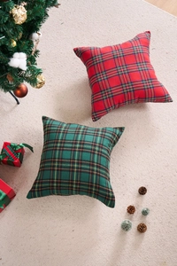 Flat lay of red and green plaid Christmas pillow covers on a cozy rug with gift boxes