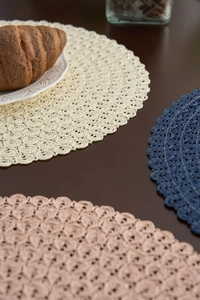 Macro detail of round woven placemats with wavy textures in cream, blue and pink