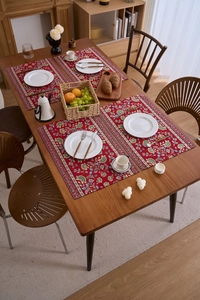 Set mit vier roten Jacquard-Platzsets mit böhmischen Blumenmustern auf Holztisch