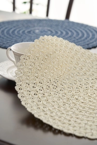 Close-up of beige round woven placemat showing intricate spiral crochet textures