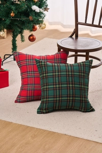 Detail of red and green plaid Christmas pillow covers on a wooden chair by a tree