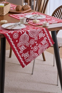 Nahaufnahme eines roten Jacquard-Tischläufers mit ethnischem Blumenmuster auf Holztisch