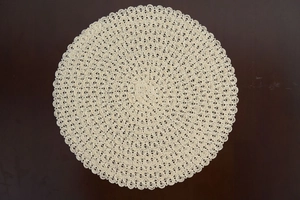 Detail of hand-woven cream circular placemat with bohemian hollow lace patterns