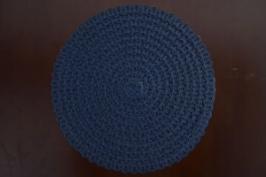 Detailed top view of a dark blue round woven placemat with decorative scalloped edges