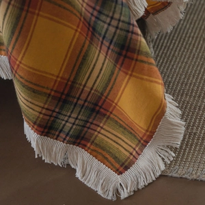 Coperta a quadretti gialla multiuso in cotone con frange bianche su pavimento ruvido