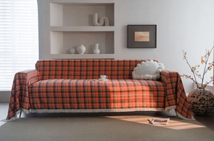 Close-up of rust red checkered sofa cover featuring cotton fabric and white fringe details