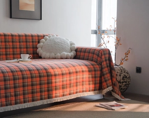 Detail showing rust red checkered sofa throw cover with soft fringe edge and woven texture