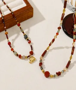 Detailed macro shot of vintage beaded necklace with red agate and small golden elephant charm