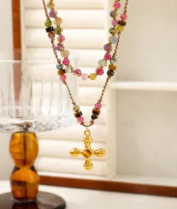 Primer plano de collar de turmalina rosa con colgante de cruz vintage y ojo de tigre