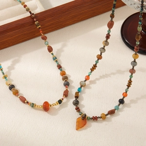Bohemian style necklace with natural stones and orange leaf pendant on white background
