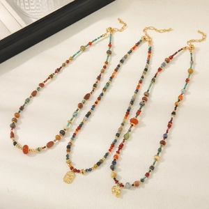 Detail of bohemian beaded necklaces with red agate, turquoise, and golden elephant pendants
