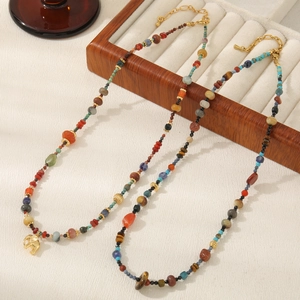 Detailed close-up of bohemian beaded necklace with gold elephant pendant and red agate stones