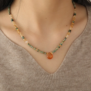 Elegant African turquoise necklace with orange water drop pendant on knitted clothing