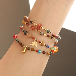 Nahaufnahme von mehrlagigen Boho-Natursteinarmbändern mit goldenem Elefantenanhänger