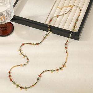 Detail einer Boho-Perlenkette mit roten und türkisen Perlen sowie goldenen Anhängern