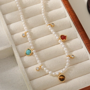 Vue macro d'un collier de perles d'eau douce avec breloques turquoise et oeil de tigre