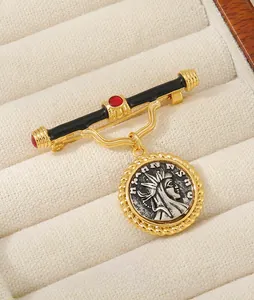 Macro detail of vintage matte gold portrait coin brooch with red gemstone accent