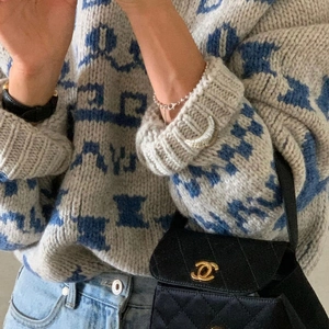 Detail shot of silver crescent brooch and bracelet on a cozy grey textured sweater
