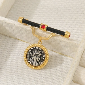 Detailed macro view of vintage gold-plated brooch with red gemstone and silver coin pendant